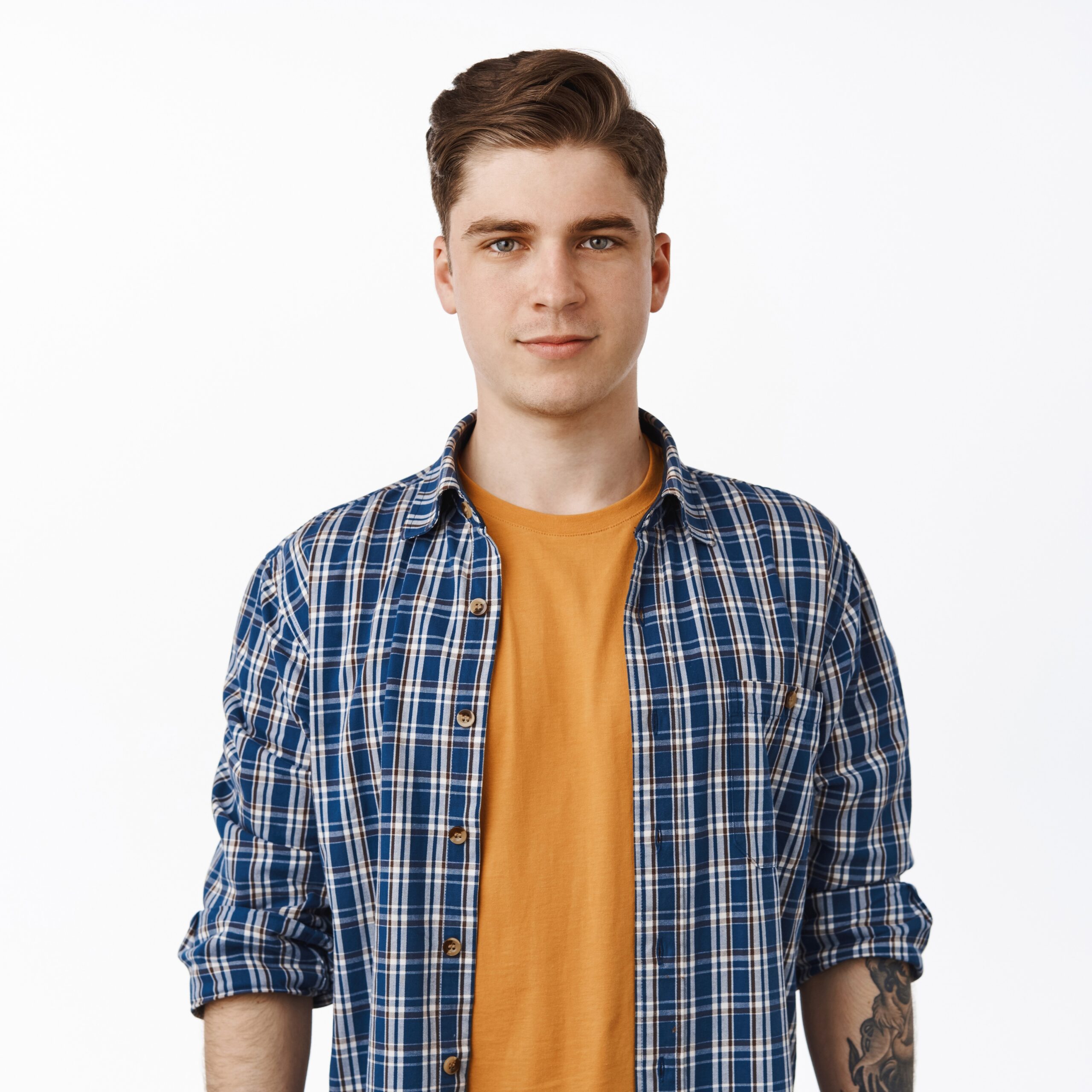 Portrait of young candid man, student boy with clean face, relaxed facial expression and casual smile, checked shirt over t-shirt, summer outfit look, white background.